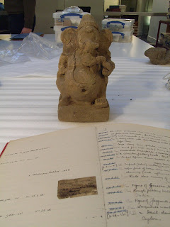 rock statue of Ganesh next to an accession book