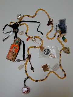 Image taken of yellow chain with multiple objects such as old film, archive tags, a Maya icon and a flask filled with dirt.